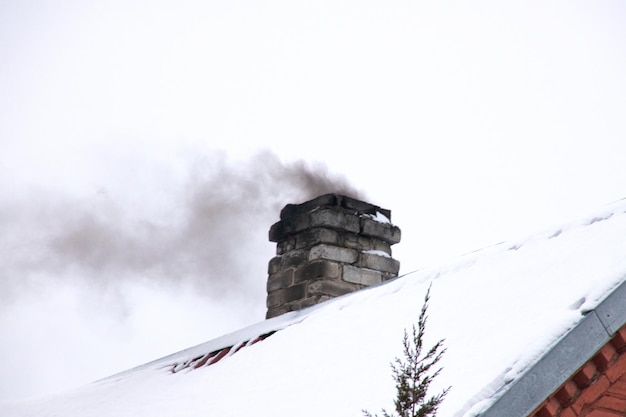 Fumée noire de la cheminée sur le toit de la maison