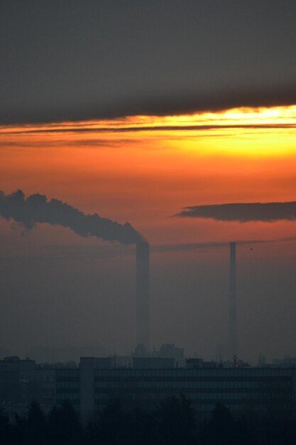 Fumée provenant de la cheminée d'usine au coucher du soleil