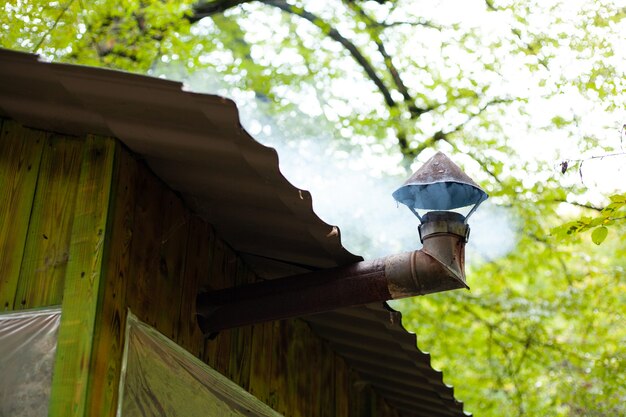 la fumée sort d'une maison en bois dans la forêt