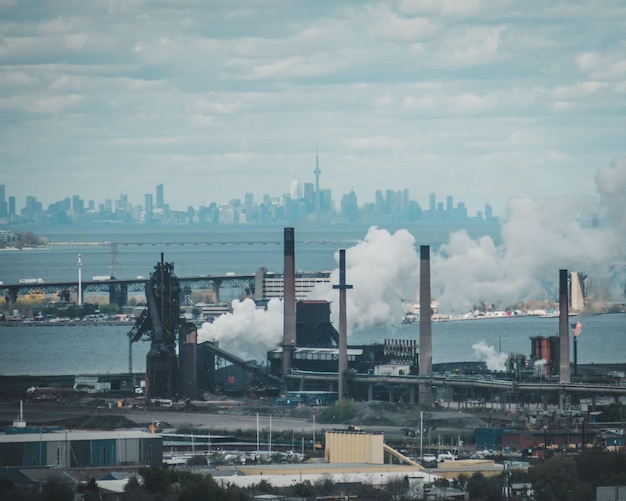 La fumée sortant des usines de Hamilton avec le pont Skyway et l'horizon de Toronto