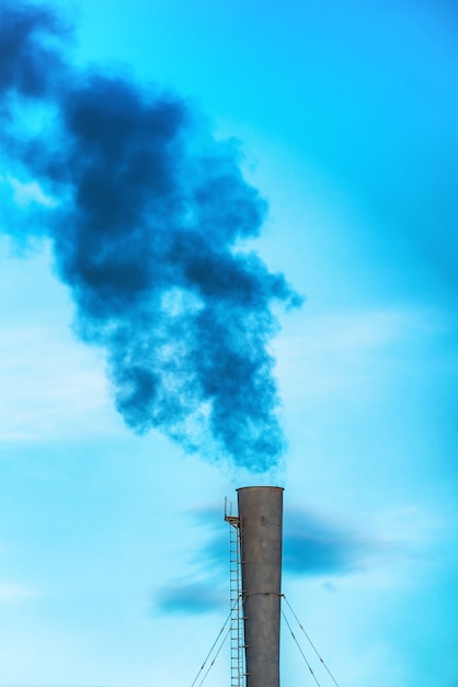 Photo fumée toxique noire industrielle de la centrale électrique au charbon sur ciel bleu