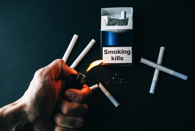 Fumer tue signe sur le paquet de cigarettes Habitude dangereuse Nocif pour la santé L'homme tient un briquet dans les mains