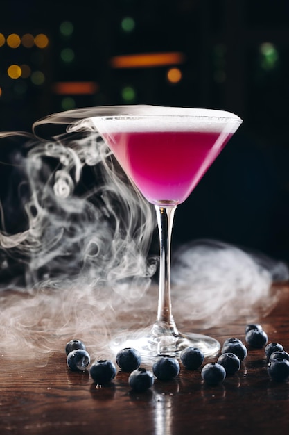 Photo fumer un verre à martini avec une boisson violette cocktail aux myrtilles