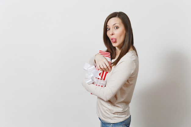 Fun femme joyeuse étreignant la boîte présente à rayures rouges avec ruban, arc isolé sur fond blanc. Pour la publicité. Saint-Valentin, Journée internationale de la femme, concept de vacances d'anniversaire de Noël.