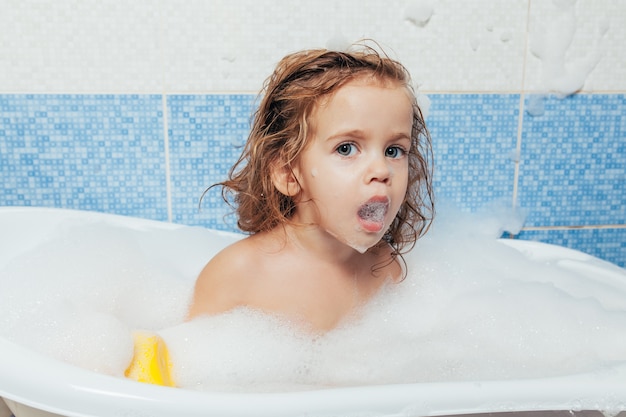 Fun joyeux bébé heureux bambin prenant un bain en jouant avec des bulles de mousse.