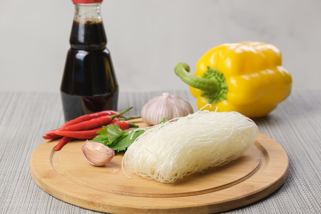 Funchose sec et ingrédients pour préparer un plat asiatique. Épices et légumes assortis sont prêts à cuisiner avec des nouilles chinoises en verre. Cuisiner des plats végétariens.