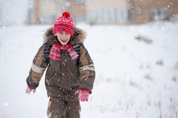 Funny boy en hiver va à l'école avec un sac à dos