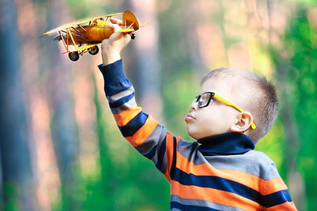 Funny boy jouant avec un avion dans le parc Concept