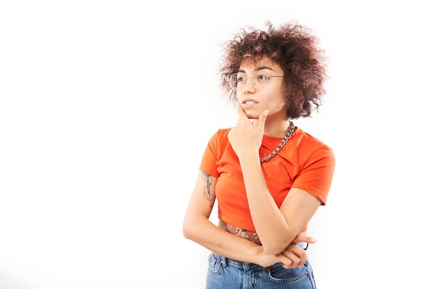 Funny curly girl holding her menton pense doutes rend décision isolé sur fond blanc studio