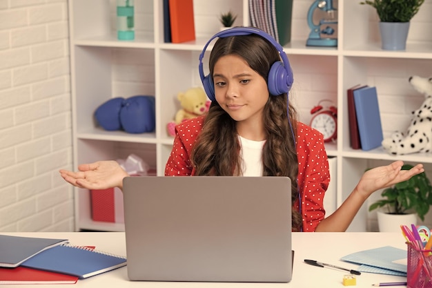 Funny face School girl étudiant assis à la table à l'aide d'un ordinateur portable lors de l'étude Happy girl face