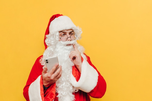 Funny Santa Claus à l'aide d'un téléphone sur fond jaune