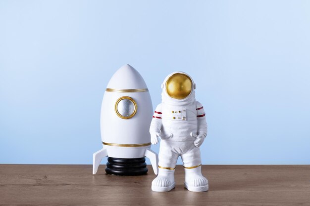 Une fusée jouet et une figurine d'astronaute Spaceman et de navette sur une table en bois sur fond bleu