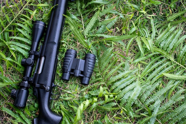 Fusil vue de dessus avec des jumelles sur le sol en herbe