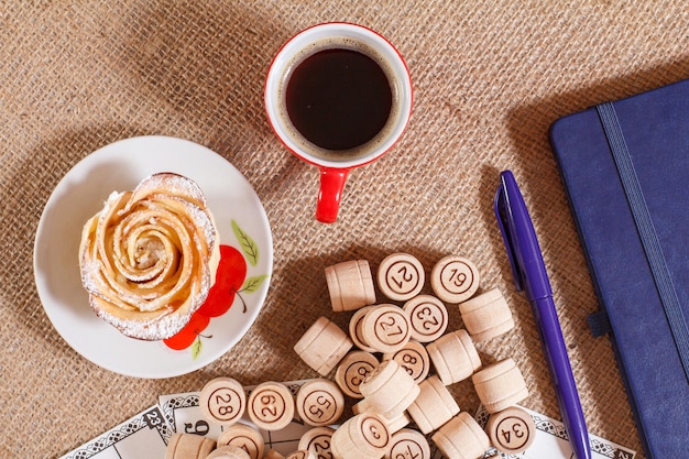 Fûts de loto en bois dans une pochette et cartes de jeu pour un jeu de loto avec une tasse de café stylo bloc-notes