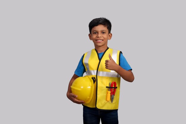 Futur architecte Indian Boy portant l'uniforme du directeur de la construction et un casque montrant les pouces vers le haut