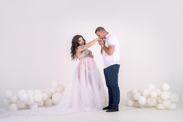 Futur père embrassant les mains de sa femme enceinte. Beau couple en studio