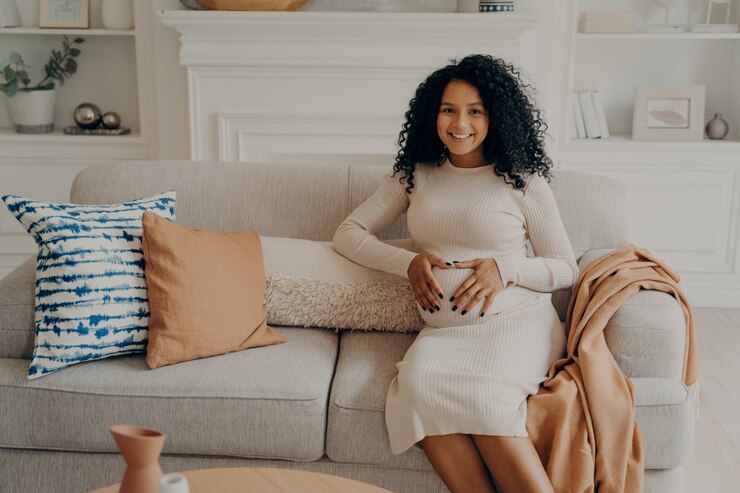 Photo future maman africaine avec un sourire éclatant sur le visage en gardant les mains jointes sur le ventre en forme de coeur