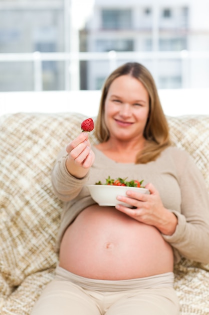 Future mère montrant une fraise à la caméra