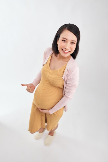 Future mère souriante et faisant un geste du pouce vers le haut isolé sur fond blanc comme concept de grossesse saine