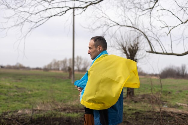 Gagnant réussi d'homme de silhouette agitant le drapeau ukrainien près d'un arbre brûlé
