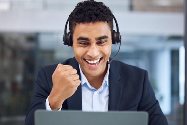 Gagnant de télémarketing et homme avec casque au bureau pour le support client CRM ou célébration Call center ordinateur portable et consultant avec pompe à poing pour le bonheur cible de vente ou contactez-nous sur le lieu de travail