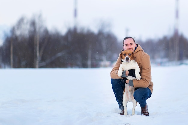 Gai homme debout avec un chien sur un pré en hiver