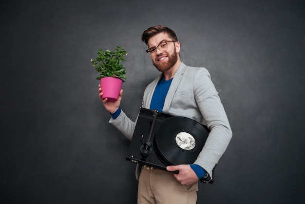 Gai jeune homme d'affaires barbu dans des verres avec des fleurs en pot et platine