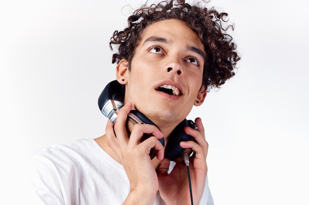 Gai mec avec des émotions de musique de technologie d'écouteurs de cheveux bouclés