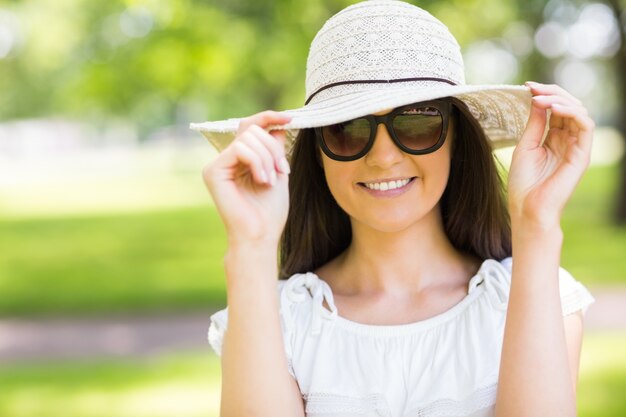 Gaie jeune femme avec des lunettes de soleil et un chapeau