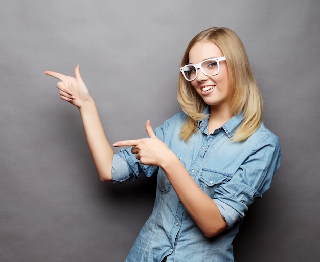 Gaie jeune femme montrant la surface, l'imaginaire visuel ou certains