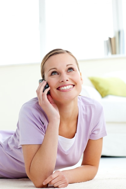 Gaie jeune femme parlant au téléphone, allongé sur le sol