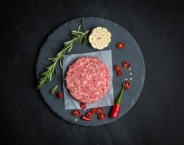 Galette de boeuf burger cru au romarin et à l'ail sur fond de cuisson sombre