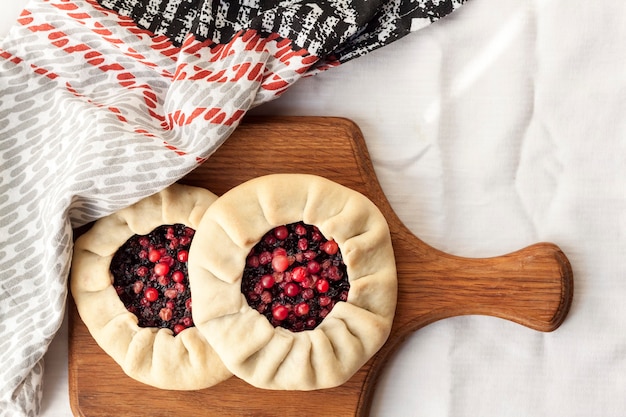 Galette sucrée maison avec des baies de sureau et des airelles rouges sur une planche de bois Vue de dessus à plat