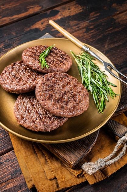 Galette de viande de boeuf burger grillé avec herbes et épices sur plaque d'acier Fond en bois Vue de dessus