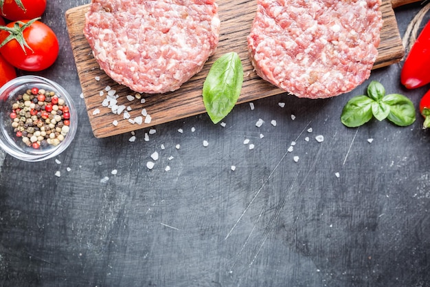 Galettes de burger de boeuf Prime Black Angus crues fraîches sur fond noir. Vue de dessus.