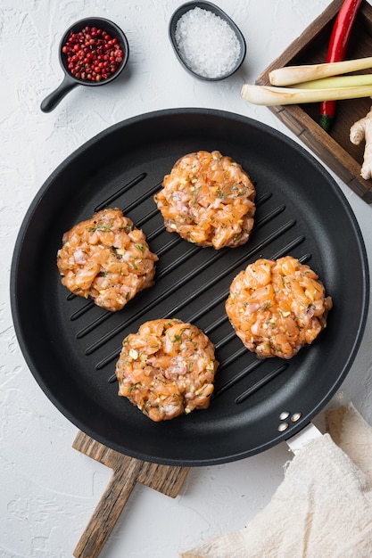 Galettes de poisson cru asiatique rapide aux herbes, sur fond texturé blanc, mise à plat