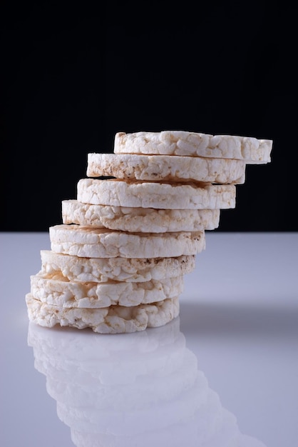 Galettes de riz par une colonne, sur un tableau blanc et un fond noir.