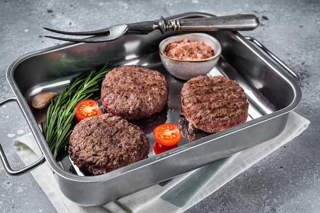 Galettes de steak de viande de boeuf burger aux herbes. Fond gris. Vue de dessus.