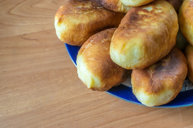 Galettes ou tartes cuites au four traditionnelles avec de la confiture sur planche de bois. Pirozhki russe frit à base de pâte de levure dans un style rustique