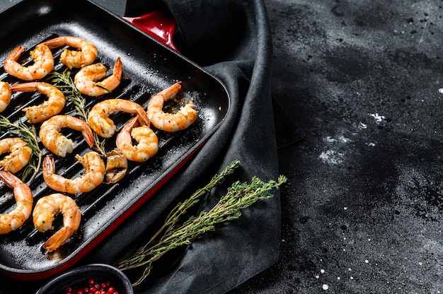 Gambas frites, crevettes dans une poêle. Fond noir