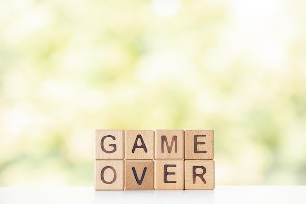 Game over est écrit sur des cubes en bois sur un fond d'été vert Gros plan d'éléments en bois