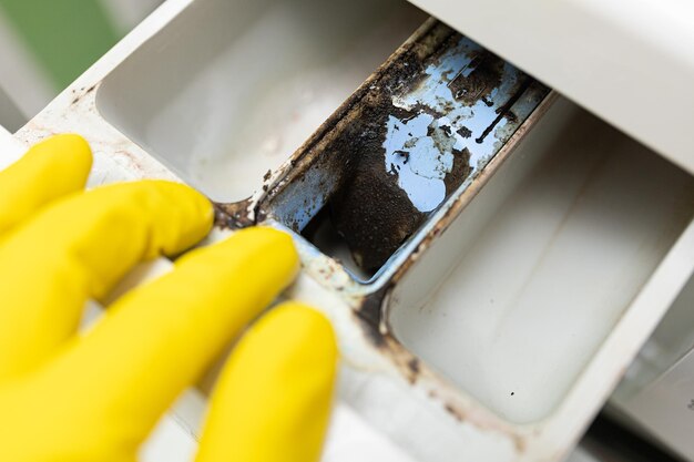 Photo gant jaune vérifier à la main ouvrir le tiroir du récipient de la machine à laver pour détecter le détergent et le conditionneur o