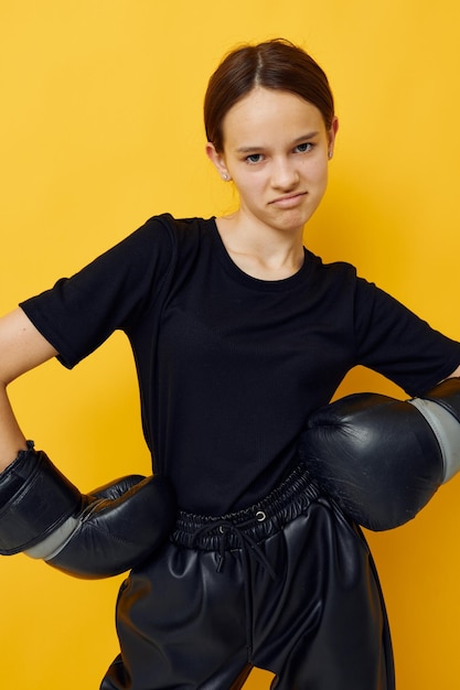 Gants de boxe noirs de jeune femme posant le sport de fond jaune