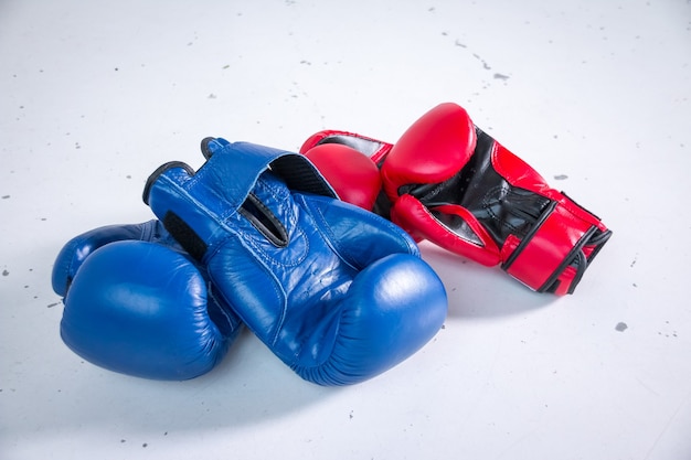 Gants de boxe rouges et bleus sur table blanche dans la chambre avec d'autres équipements sportifs