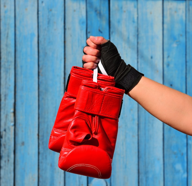 Photo gants de boxe rouges suspendus à une corde dans la main d'une femme