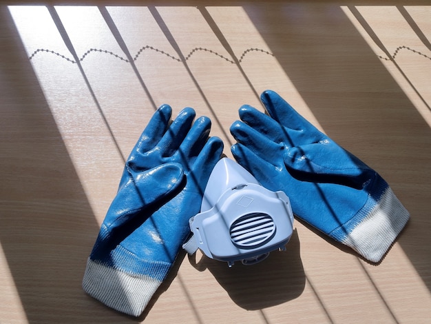 Photo des gants en caoutchouc durables bleus et un respirateur sont à la surface de la table