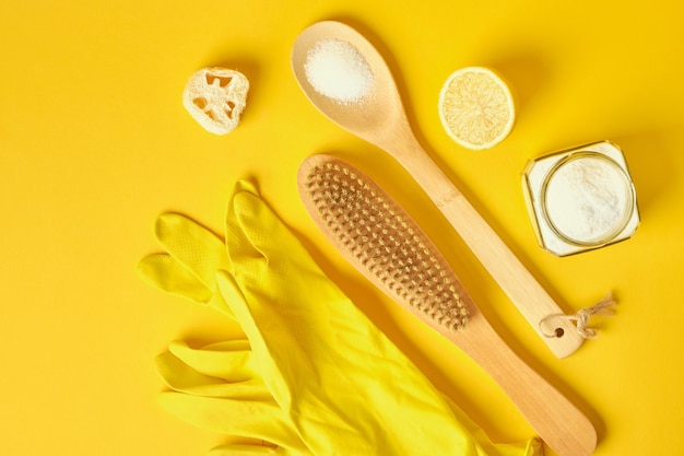 Gants en caoutchouc soda brosse éponge citron et luffa sur fond jaune concept zéro déchet