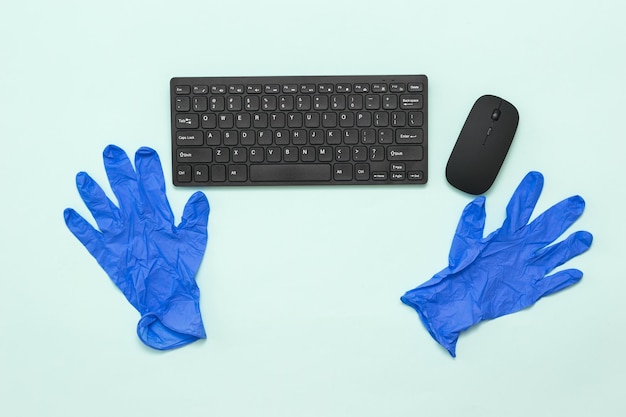 Gants médicaux bleus et clavier noir avec une souris sur fond clair Prévention de la propagation du coronavirus