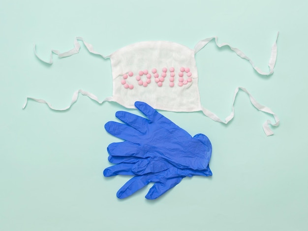 Gants médicaux et masque avec des pilules sur fond bleu clair Prévention de la propagation du coronavirus