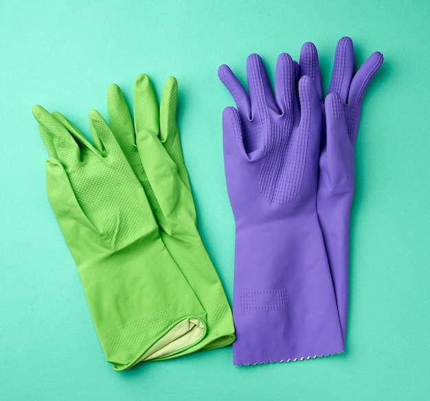 Gants de nettoyage en caoutchouc vert et violet sur une surface verte